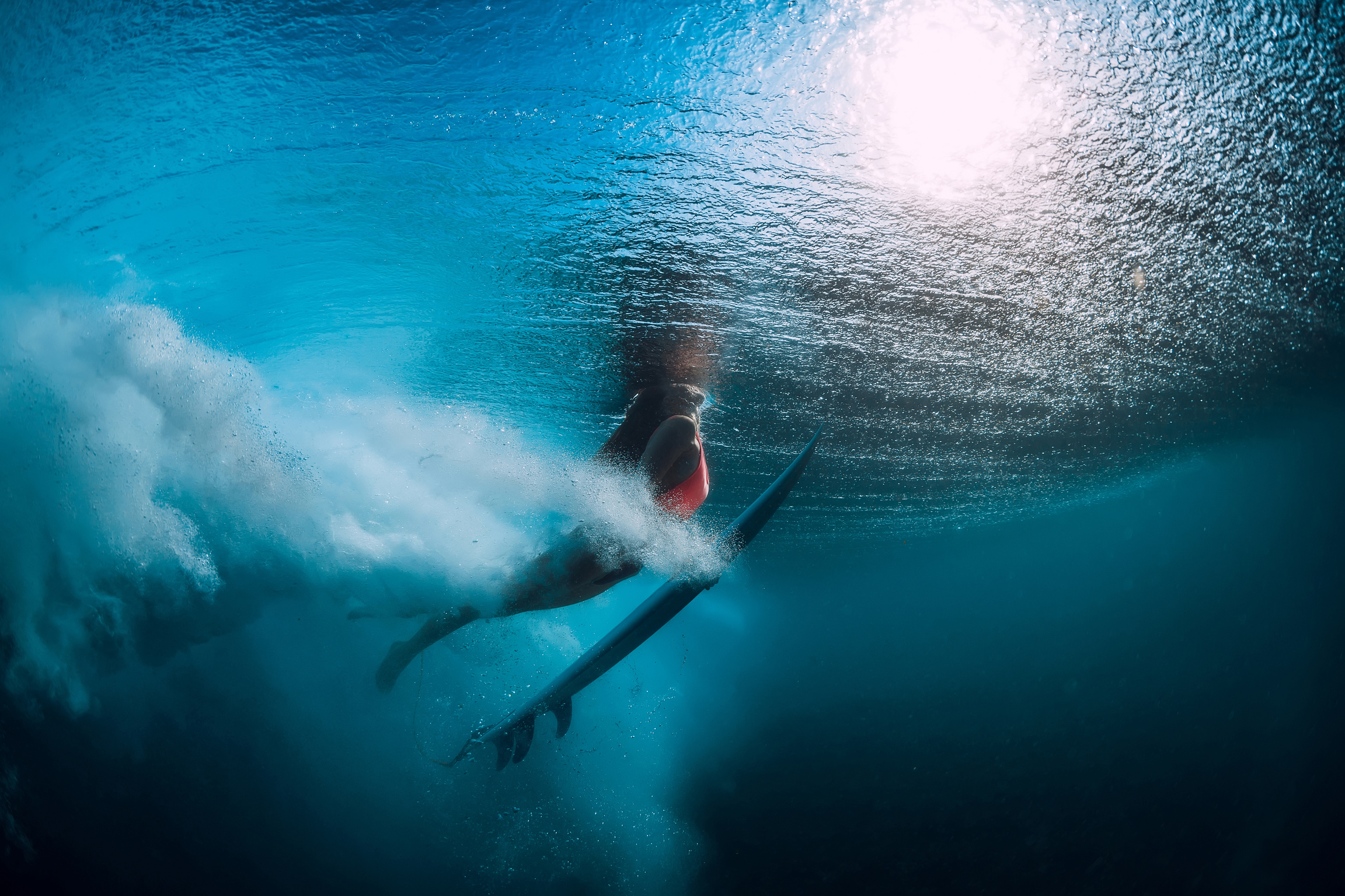 Surf girl with surfboard dive underwater with under big wave.